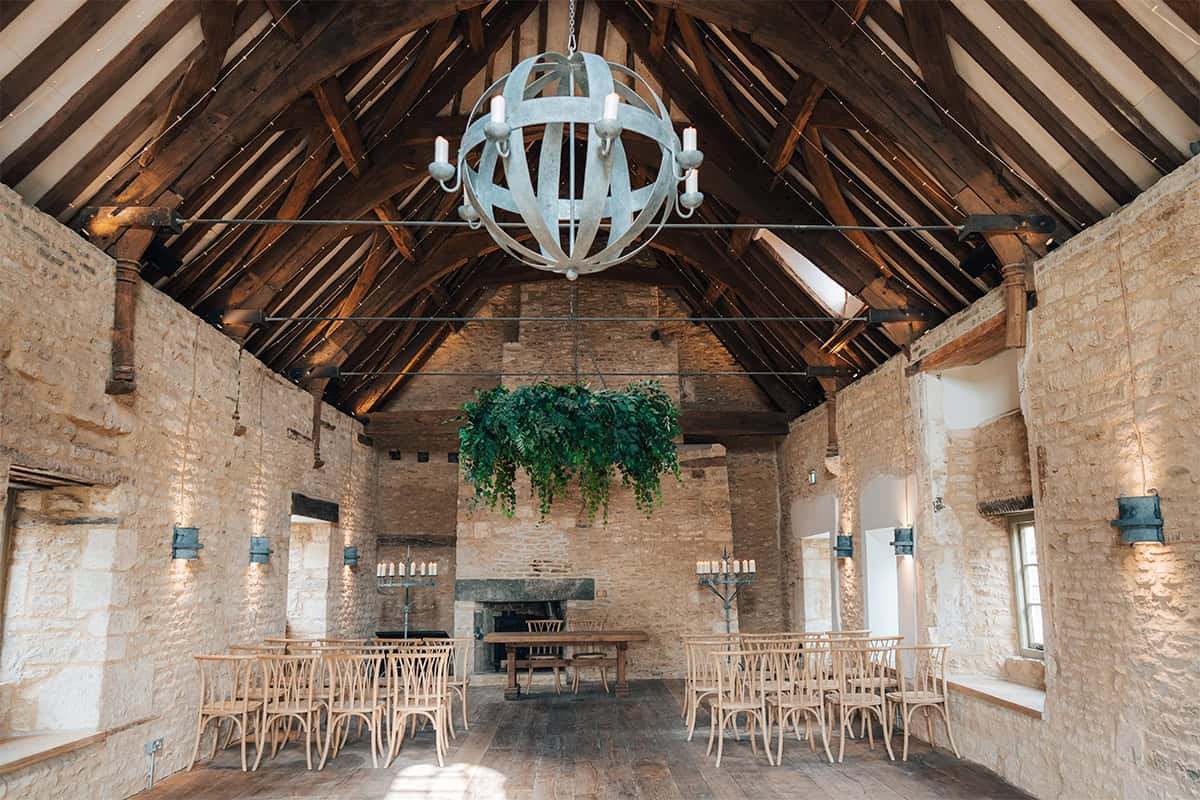 Ivy Lodge ceremony barn with medieval oak roof trusses, globe chandelier, and Cotswolds stone walls